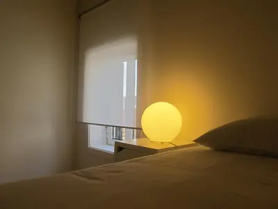 a bed with a yellow lamp next to a window at Oporto City Cottage in Porto