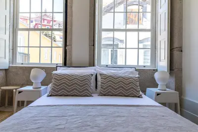 a bedroom with a large bed with two windows at Vitoria Studio Residence II - Downtown in Porto
