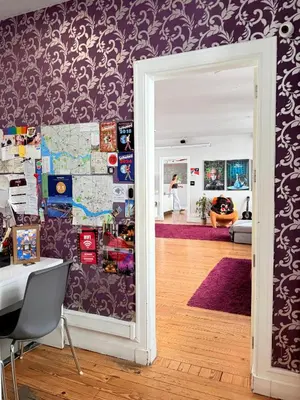a room with a desk and a wall with purple wallpaper at Rivoli Cinema Hostel in Porto