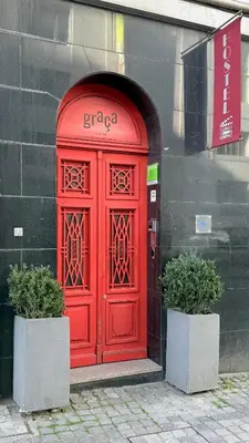 a red door on a building with two plants at Rivoli Cinema Hostel in Porto