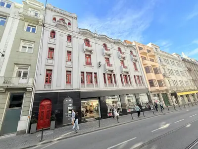 a large white building with red doors on a street at Rivoli Cinema Hostel in Porto