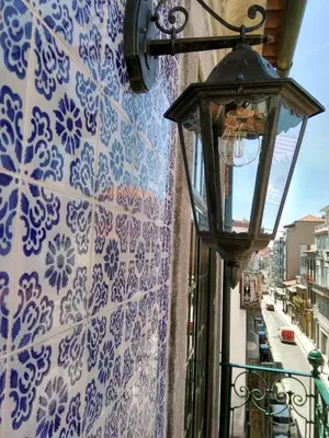 a street light on a wall with blue and white tiles at Azulejos Duplex Apartment - Porto Downtown in Porto