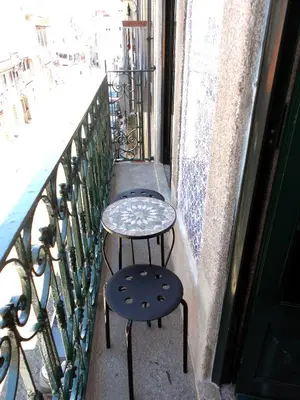 a couple of tables and stools on a balcony at Azulejos Duplex Apartment - Porto Downtown in Porto