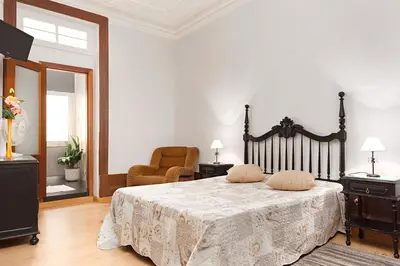 a bedroom with a bed and a chair and a mirror at Almada Guest House in Porto