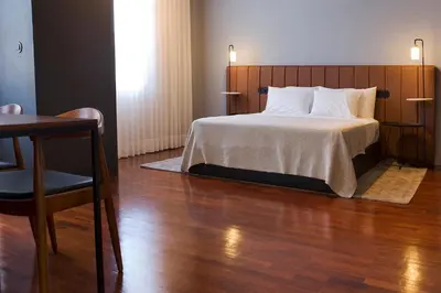 a bedroom with a bed with a wooden headboard and a table at Oporto Cozy Design Studio - Solar da Avenida in Porto