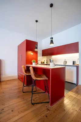 a kitchen with red cabinets and a red island with chairs at Calacatta Housing in Porto