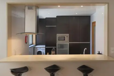 a kitchen with black cabinets and a counter with stools at Republica Deluxe Apartment in Vila Nova de Gaia