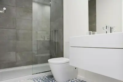 a bathroom with a white toilet and a shower at My Modern Homey at Porto in Porto