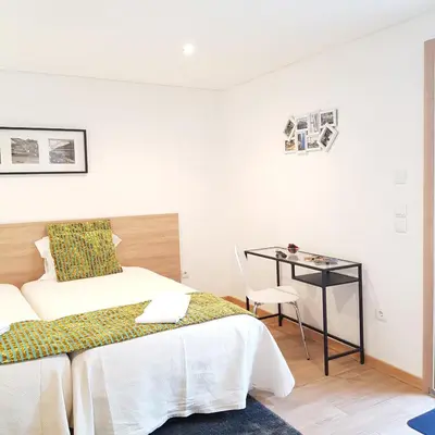 a white bedroom with a bed and a desk at À Francos Metro in Porto
