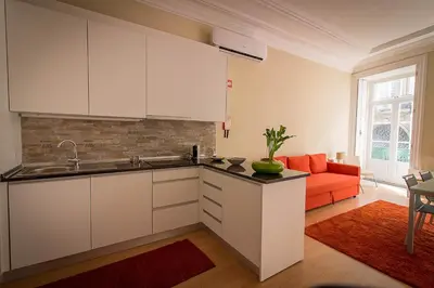 a kitchen with white cabinets and a red couch at São Domingos Flowers Apartments in Porto