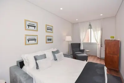 a white bedroom with a bed and a chair at Rosario's Boutique Apartments in Porto
