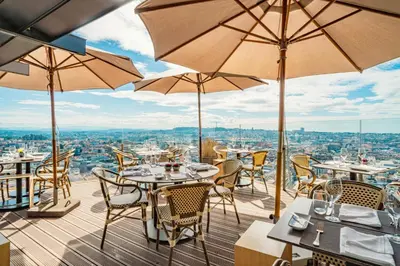 a balcony with tables and chairs and a view of a city at Hotel Dom Henrique - Downtown in Porto