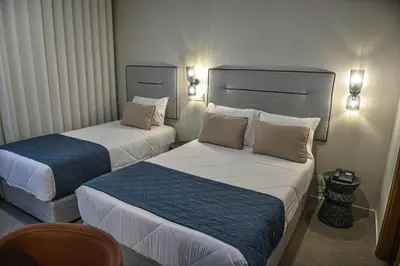 a hotel room with two beds and a chair at Hotel America in Porto