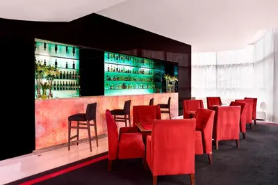 a restaurant with red chairs and a bar with wine bottles at Sheraton Porto Hotel & Spa in Porto