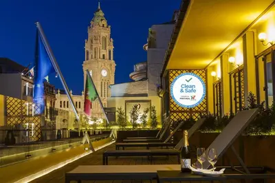 a restaurant with tables and a clock tower at night at Pao de Acucar Hotel in Porto