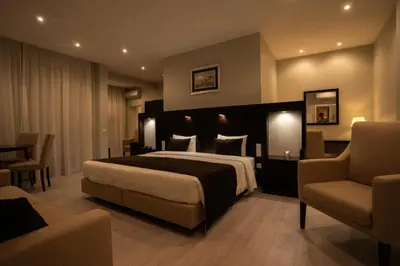 a hotel room with a bed and two chairs at Pao de Acucar Hotel in Porto