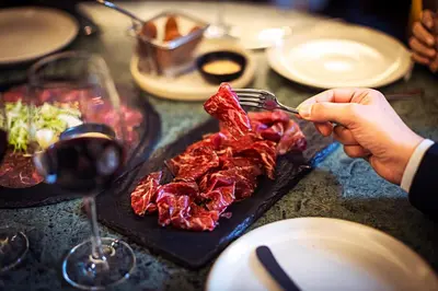 a person eating meat on a plate with a glass of wine at Pestana Vintage Porto Hotel & World Heritage Site in Porto