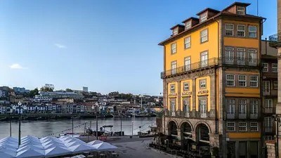 a tall yellow building next to a river at Pestana Vintage Porto Hotel & World Heritage Site in Porto