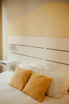 a bed with a white headboard and two pillows at H.ö.H in Porto