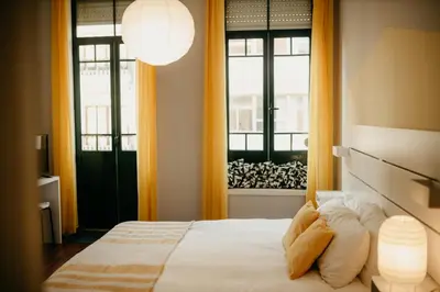 a bedroom with a bed and two windows at H.ö.H in Porto