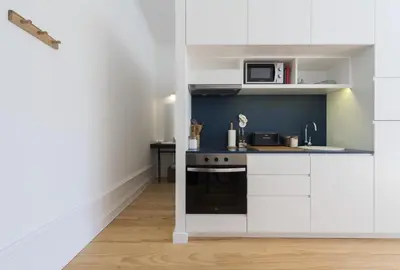a kitchen with white cabinets and a stove top oven at Tripas-Coração, São Bento Apartments in Porto