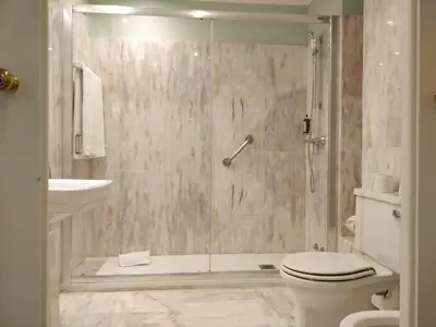 a bathroom with a shower with a toilet and a sink at Grande Hotel do Porto in Porto