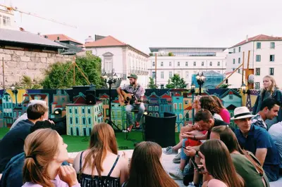 a group of people sitting on the ground watching a man playing music at CATS Porto Hostel in Porto
