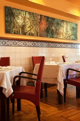 a dining room with two tables and chairs and a painting at Hotel Internacional Porto in Porto
