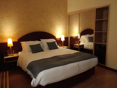 a large bed in a hotel room with two lamps at Hotel Internacional Porto in Porto