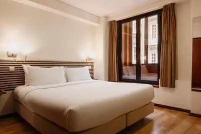 a bedroom with a large white bed and a window at Hotel da Bolsa in Porto