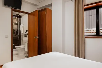 a bedroom with a bed and a bathroom with a toilet at Hotel da Bolsa in Porto