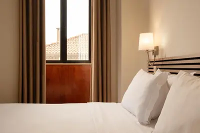 a bedroom with a bed with white pillows and a window at Hotel da Bolsa in Porto