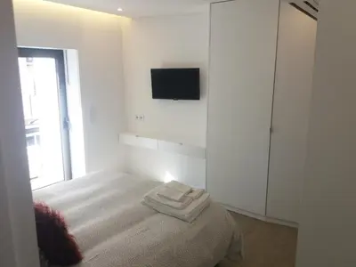 a white bedroom with a bed and a tv on the wall at SantOporto Baixa in Porto