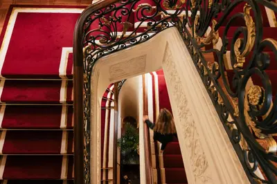 a woman walking down the stairs in front of a mirror at Infante Sagres - Small Luxury Hotels Of The World in Porto