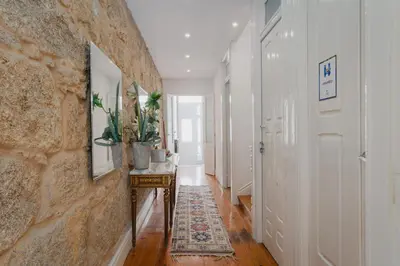 a hallway with white walls and a stone wall at Ndussole Guest House in Porto