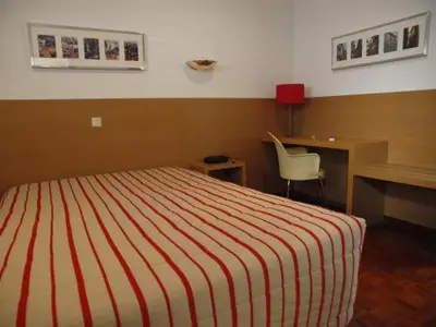 a bedroom with a bed and a desk and a chair at Costa do Sol B&B in Porto