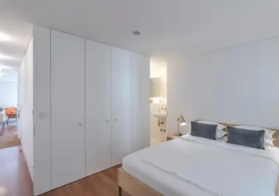 a bedroom with white walls and a bed with blue pillows at Oporto Street das Aldas - River View in Porto