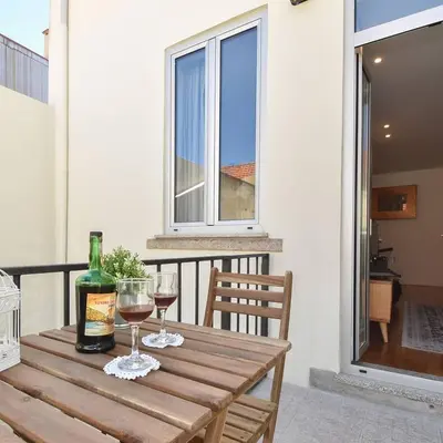 a wooden table with two glasses of wine on a balcony at Oporto Lovely House in Porto
