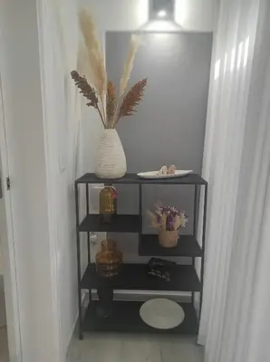 a black shelf with a vase and flowers on it at Oporto Lovely House in Porto