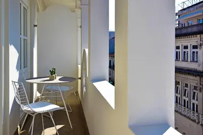 a small table and chairs on a balcony with a window at My Story Apartments Porto - Santa Catarina in Porto