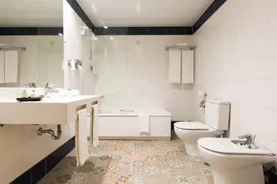 a bathroom with two sinks and a toilet and a tub at Legendary Porto Hotel in Porto