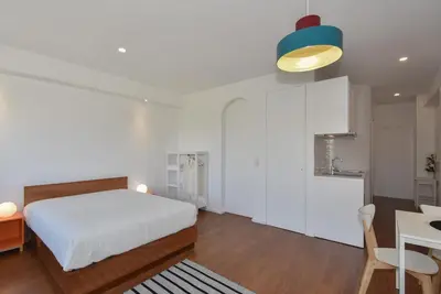 a bedroom with a bed and a table and a kitchen at Porto Republica Flat in Porto