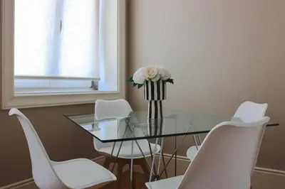 a glass table with white chairs and a vase with flowers at Magalhães Prime in Porto