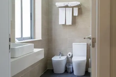 a bathroom with a white toilet and a sink at Porto Domus Hotel in Porto