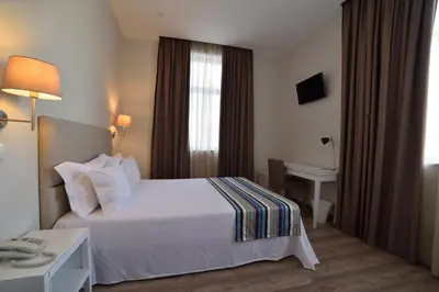 a hotel room with a white bed and a desk at Porto Domus Hotel in Porto