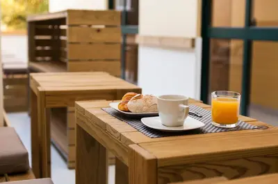 a table with a cup of coffee and a plate of bread and orange juice at Boavista Guest House in Porto