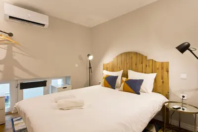 a bedroom with a large white bed with a wooden headboard at Duque de Loulé in Porto