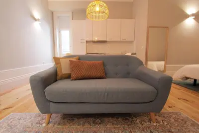 a gray couch in a living room with a kitchen at Duque de Loulé in Porto