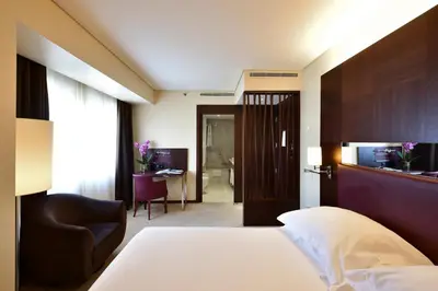 a hotel room with a bed and a chair at Porto Palácio Hotel by The Editory in Porto