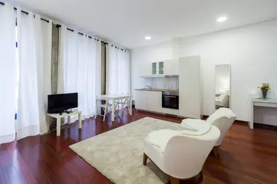 a living room with white furniture and a television at Flores Studio in Porto